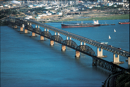 Ariel view of the Benicia-Martinez Bridge toll plaza with many cars waiting to go through.